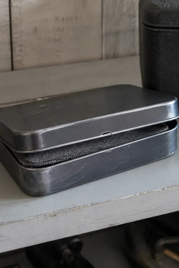 Gunmetal gray Altoids wallet with scuffed highlights and a dark elastic strap