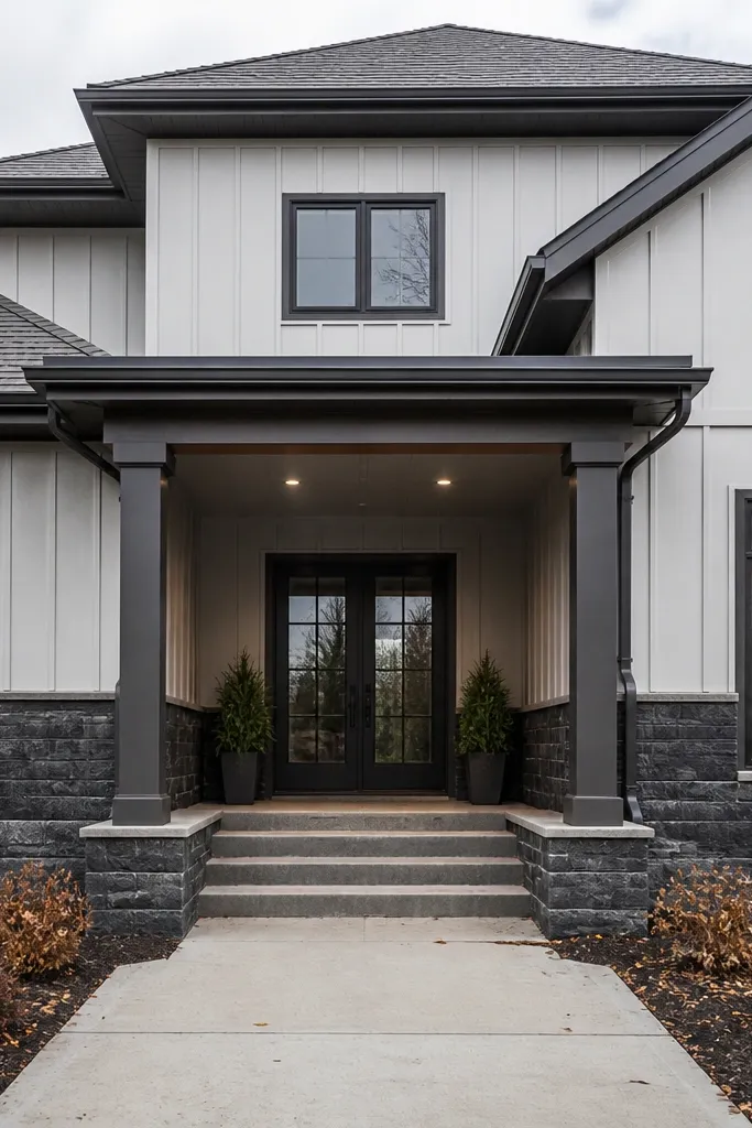 Pale gray upper facade with dark stone-look base cladding and a modern entry