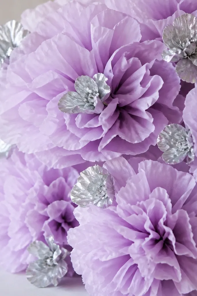 Lilac tissue paper flowers paired with small silver metallic tissue flowers. The silver pieces catch light and appear as mini blooms scattered through the lilac clusters.