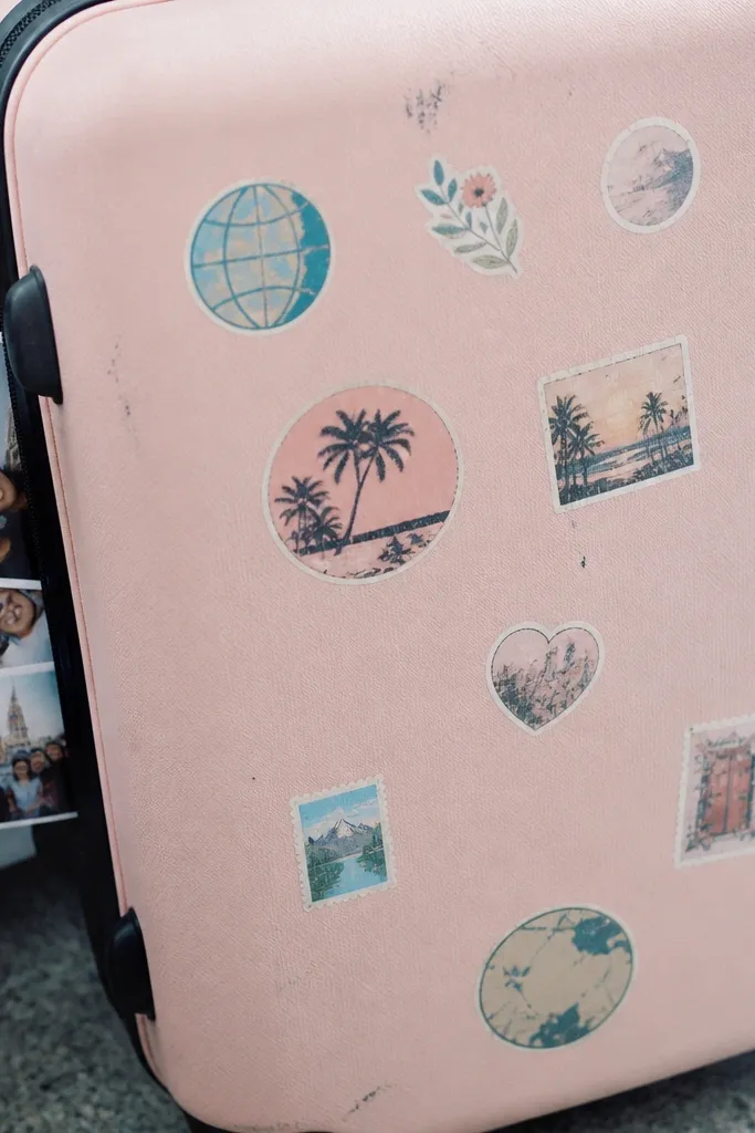 Pastel suitcase with travel stickers and luggage tags on a light background