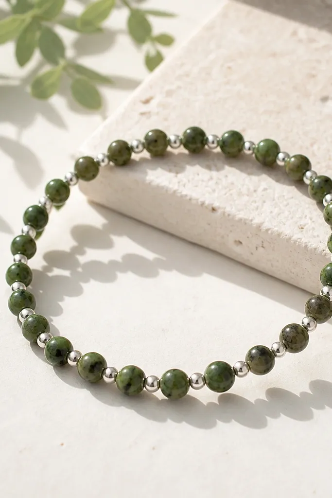 Speckled green clay beads (9mm) mixed with tiny silver stud-like beads (3mm) in a tight repeating pattern, bracelet shown in bright daylight.