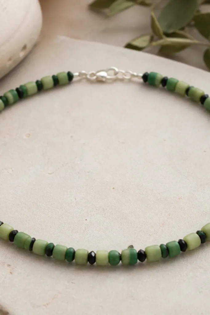 Green clay rounds in two shades separated by black faceted spacer beads (4mm), with a silver clasp and a tight, uniform pattern.