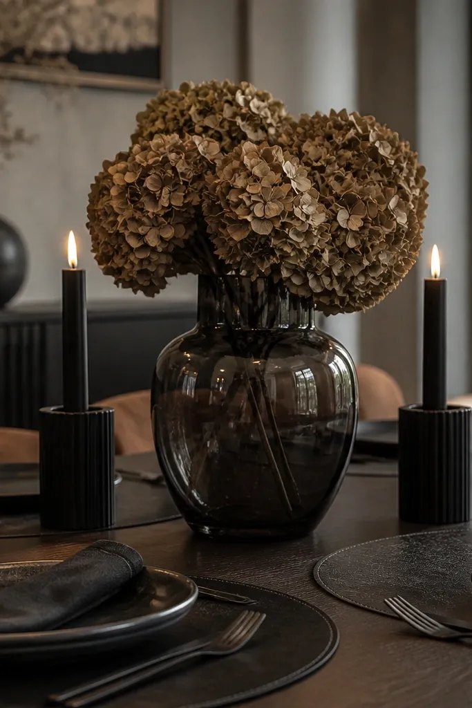 Smoked glass vase with dried hydrangea heads and two black candles