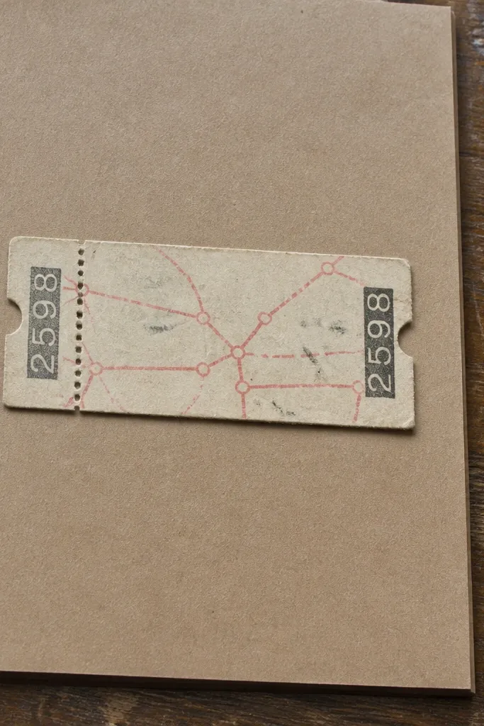 Faded cream ticket stub with perforation dots and a route line