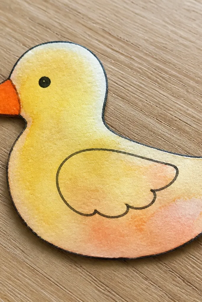 Yellow duck silhouette with watercolor wash edges and orange beak