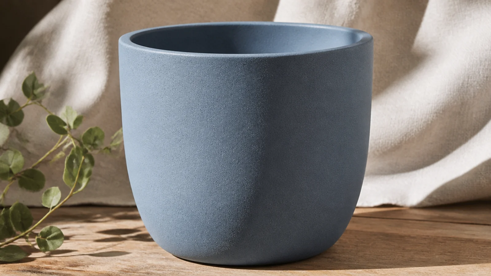 A weatherproof outdoor pot in dusty blue with a durable, slightly satin finish standing on a sunny step, showing paint that has held up outdoors.