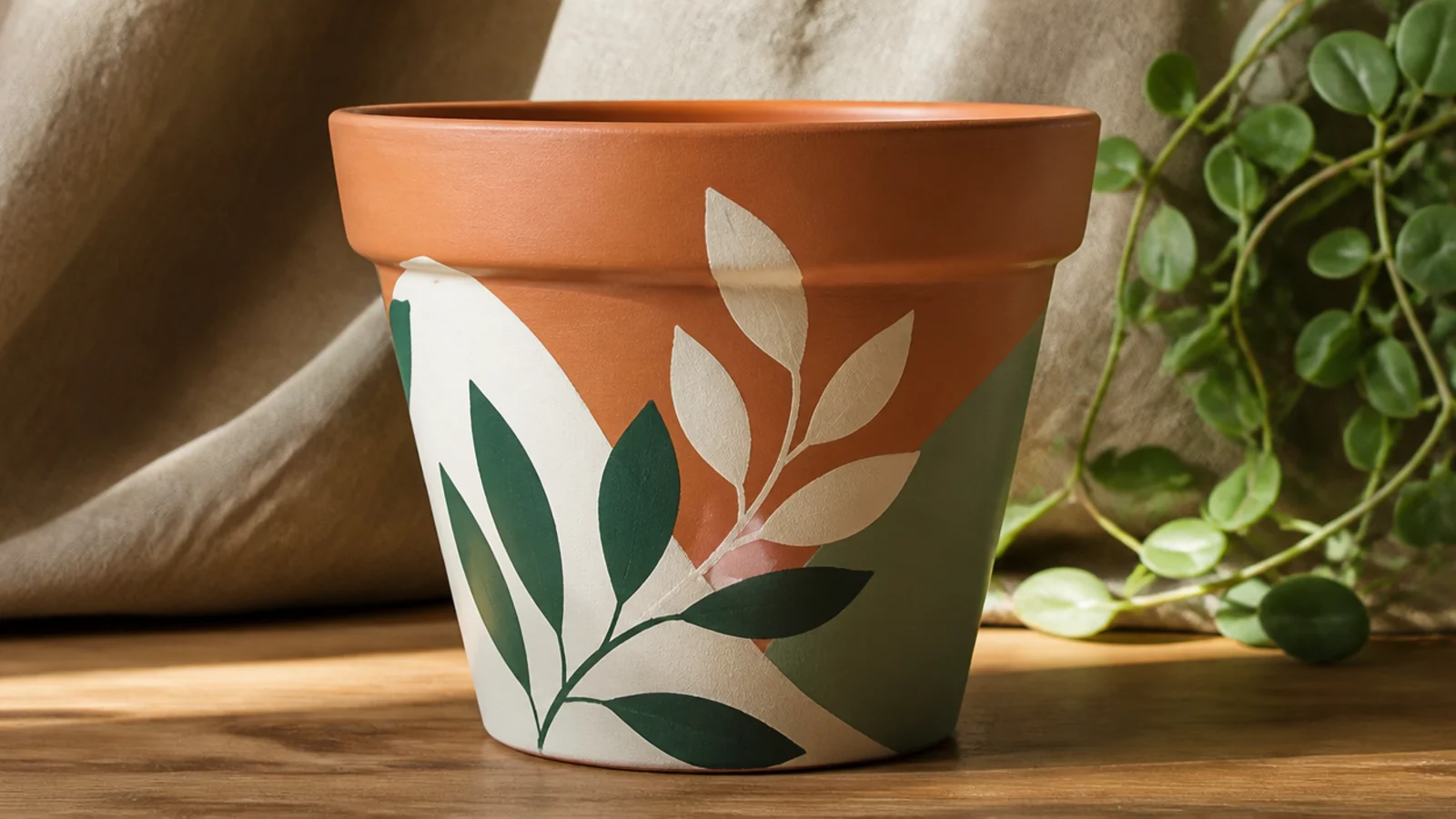 A finished terracotta pot with a hand-painted design under a subtle even satin sheen, showing a clear protective topcoat over the color.