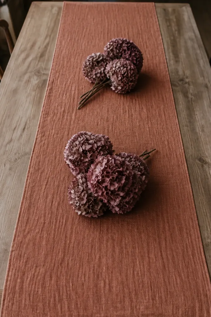 Rust linen runner with dried hydrangea blooms on a dining table