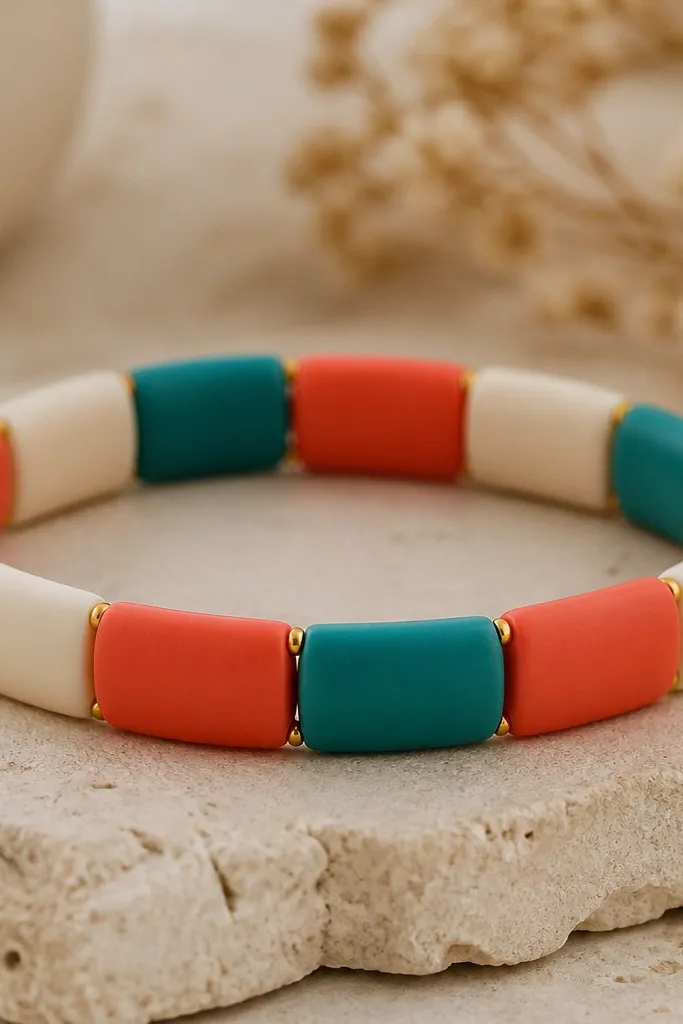 A bracelet that looks like thick stripes. Blocks of solid clay beads alternate: coral, cream, and teal, with no spacers except tiny gold dots at the edges of each block.