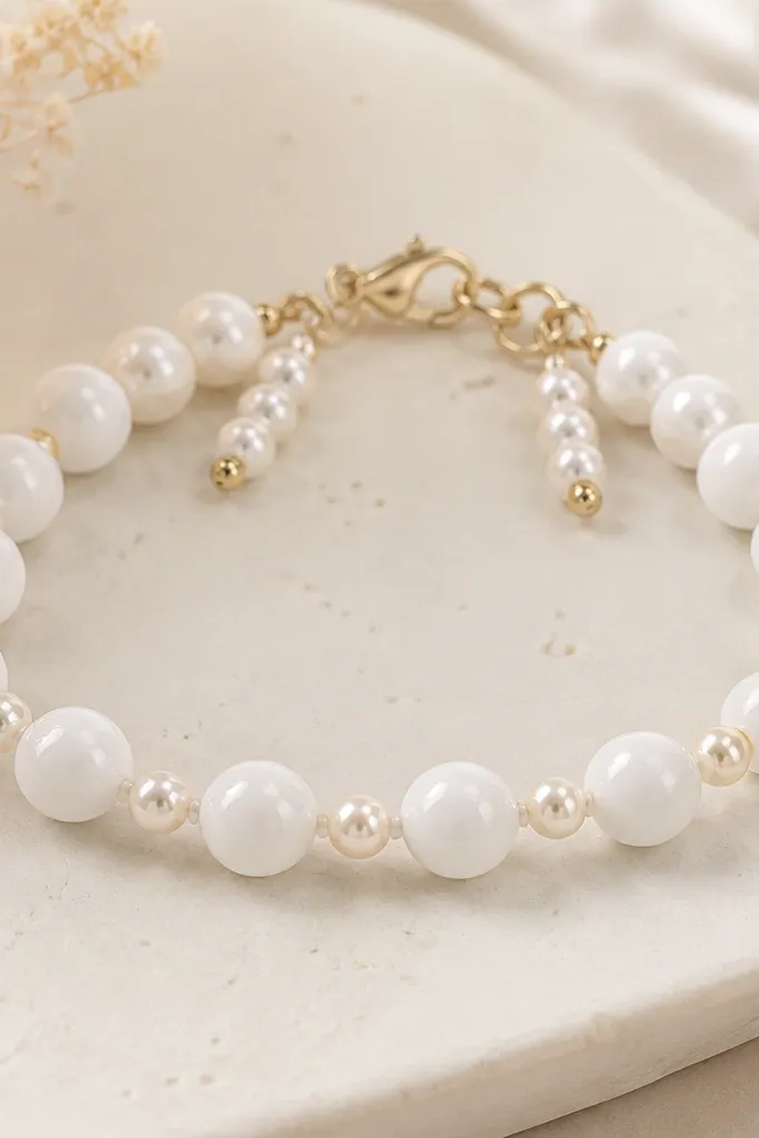 A bracelet with glossy white clay beads paired with tiny pearl-like beads on both sides. Two short pearl drop sections sit near the clasp, giving a slight swing.