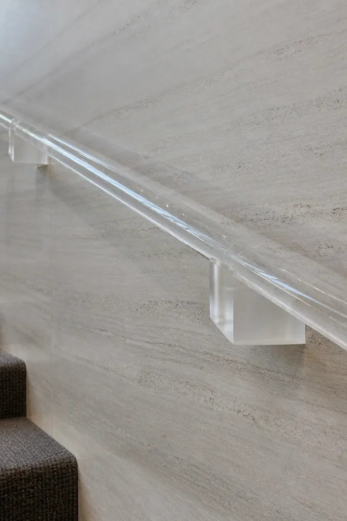 Clear acrylic handrail with minimal edge-grip mounts along a stair