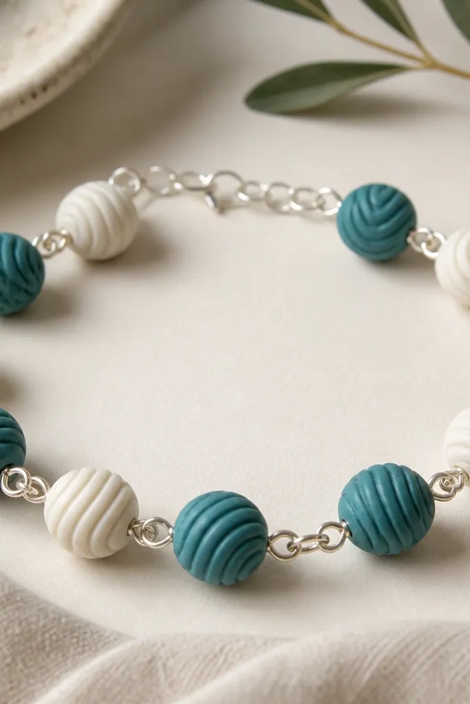 A teal and white bracelet with wave-texture clay beads alternating, plus small silver jump rings between sections.