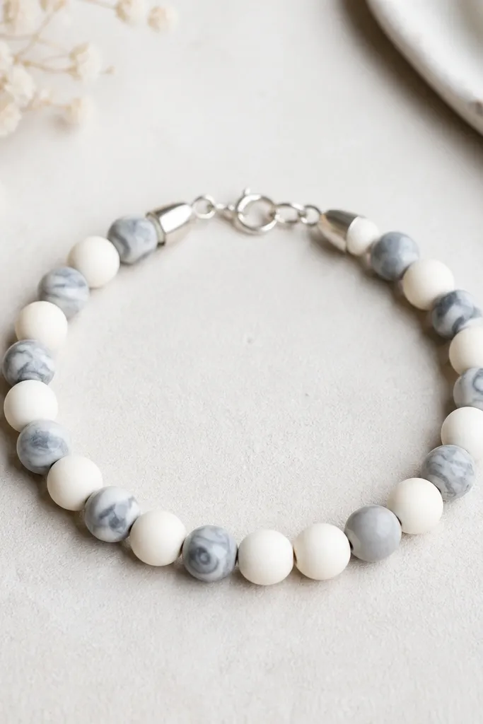 A bracelet laid flat: matte white clay beads alternate with gray marble clay beads, finished with neatly covered silver crimps and a simple clasp.