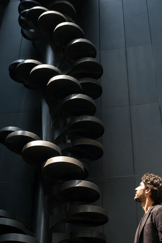 Black spiral staircase with large round tread caps and a simple rail