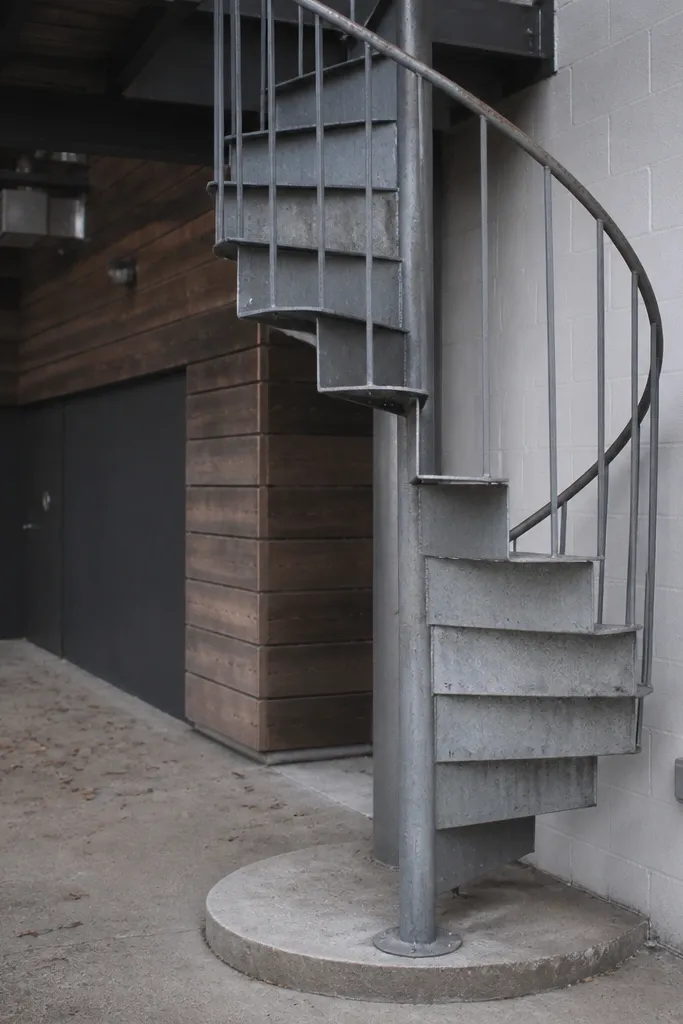Galvanized gray spiral staircase with step treads painted to look riveted