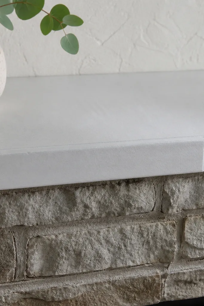 White tile ledge across the top of stone fireplace with straight grout lines