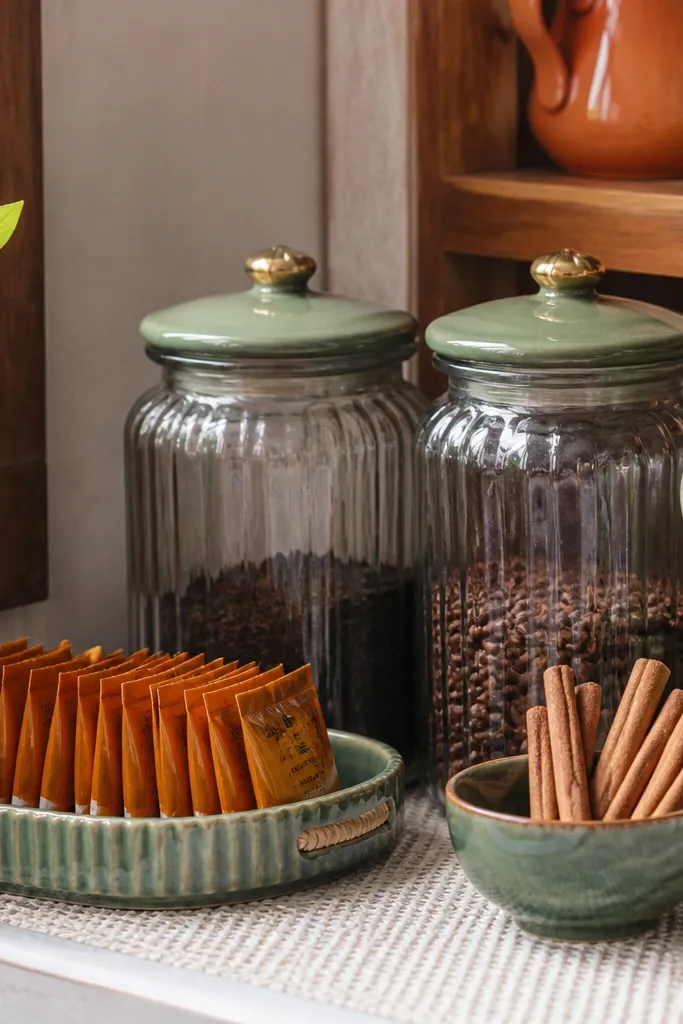 Green-lidded jars and chai packets organized on a small shelf corner