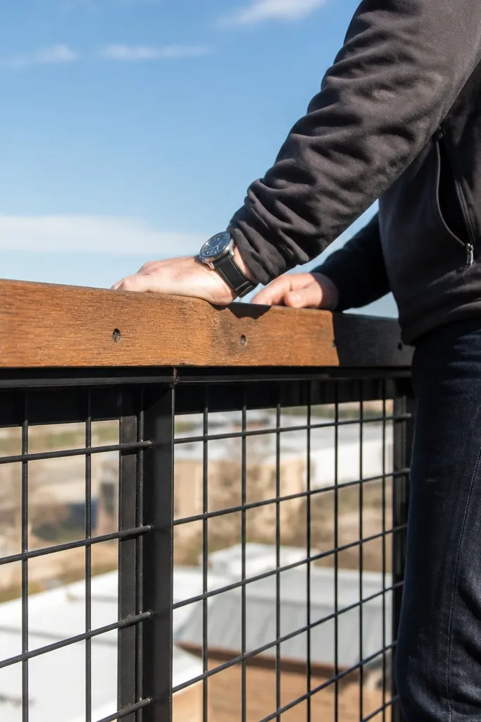 Welded grid metal railing with reclaimed wood top cap