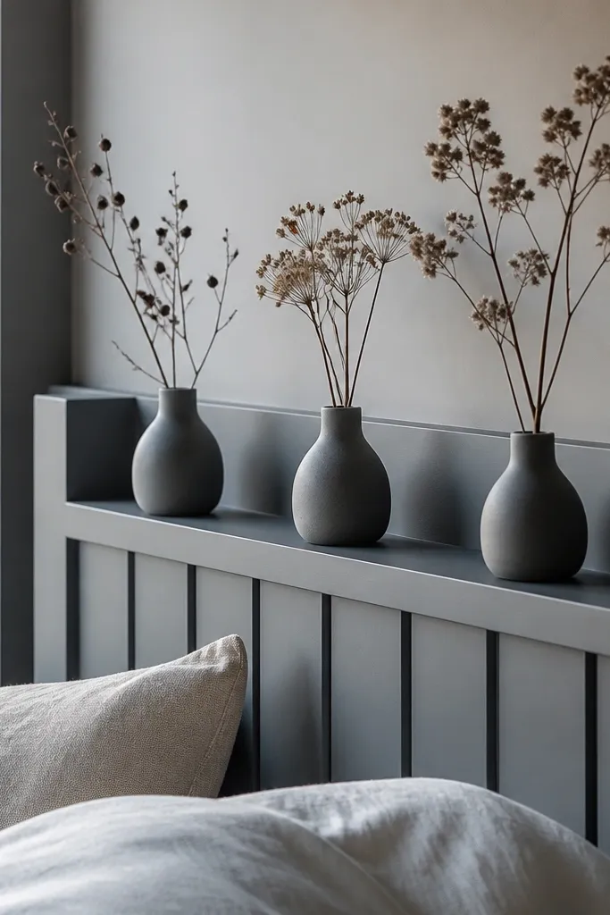 Grey headboard with a small shelf holding grey ceramic bud vases